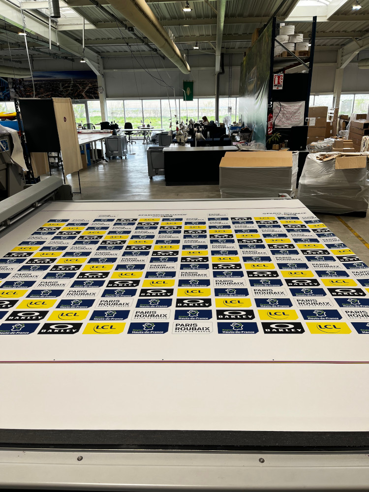 Photo : impression en atelier du mur d'image Paris-Roubaix — grille step-and-repeat en cours d'impression