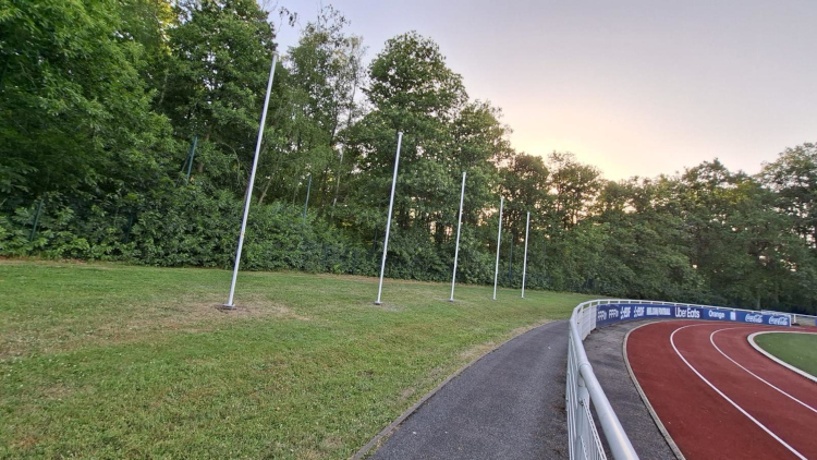 Pose d'une rangée de mâts pour drapeaux au Centre National du Football de Clairefontaine — fourniture et installation Doublet. Vue d'ensemble — rangée de mâts posés à Clairefontaine, bord de terrain d'athlétisme