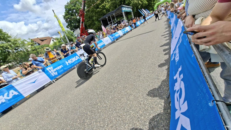 L'habillage barrières HOKA sur le parcours du Challenge Roth — des kilomètres de communication continue, de la route au pont, en cohérence totale avec la charte de la marque. Habillage barrières sur pont — effet tunnel bleu HOKA