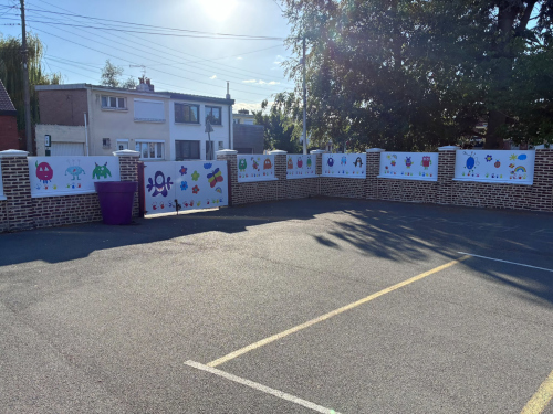 Les dessins des enfants de l'école Le Frênelet imprimés en grand format sur les murs de la cour — une décision pédagogique autant qu'esthétique. Panneaux monstres/personnages — vue de la cour